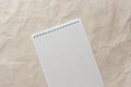 Gray notepad with white coiled spring on a background of beige crumpled craft paper
