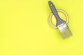 Gray paintbrush with can of yellow paint on trendy yellow background Royalty Free Stock Photo
