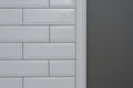 Gray painted wall, part of the wall is covered tiles small white glossy brick, ceramic decorative molding tiles. Fragment of the w Royalty Free Stock Photo