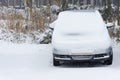 Gray parked car covered with a thick layer of snow