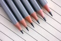 Gray pencils on lined paper background. Royalty Free Stock Photo