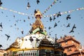 Gray pigeons in flight around stupa in beautiful Durbar Square in the picturesque city of Kathmandu. Pigeons fly around a sacred