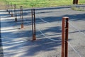 Gray pillars separating the park path from the road. deliberately rusty steel bollards bent into a double space slot connected by Royalty Free Stock Photo