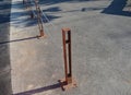 Gray pillars separating the park path from the road. deliberately rusty steel bollards bent into a double space slot connected by