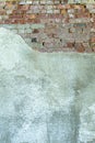 Gray plastered old brickwall with chipped stucco pieces. Grunge red and white brick wall with damaged surface background Royalty Free Stock Photo