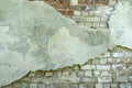 Gray plastered old brickwall with chipped stucco pieces. Grunge red and white brick wall with damaged surface background Royalty Free Stock Photo