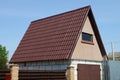 Gray plastic attic of a private rural house with one window under a brown tiled roof Royalty Free Stock Photo