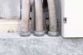 Gray plastic pipe joints for electrical cables attached to aluminum pipes on concrete pillar.
