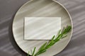 Gray plate with a white invitation card on a gray background closeup