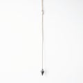 Gray Plumb Bob Hanging from Thin Tan Cord Against a Clean White Background Royalty Free Stock Photo