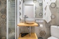 Gray polygonal ornamental tiles in bathroom with a glassed-in shower and vanity sink. Concept of stylish designer
