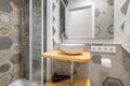 Gray polygonal patterned tiles in a bathroom with glassed-in shower and sink. Concept of a stylish designer bathroom in