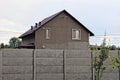 Gray private house with windows behind a concrete fence Royalty Free Stock Photo