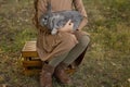 A gray rabbit is sleeping in the arms of a girl sitting on the grass