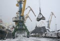 Autumn bad weather, snow, loading coal into the holds of industrial ships in the seaport Royalty Free Stock Photo