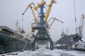 Autumn bad weather, snow, loading coal into the holds of industrial ships in the seaport Royalty Free Stock Photo