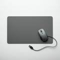 Gray rectangular mouse pad with a dark gray wired optical mouse placed on it. The Royalty Free Stock Photo
