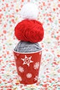 Gray, red and white ball for knitting and red Christmas cup on the background