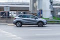 Gray Renault Captur driving on a city road. Side view of compact crossover Renault Kaptur speeding in industrial district of town
