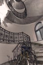 Gray round spiral staircase with black railings with patterns and bicycle view from down