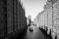 Gray-scale shot of boat in the river with a building on the side in Hamburg, Germany