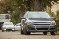 Gray shiny car parked in quiet area on asphalt road on blurred bokeh background on bright sunny day. Transportation and parking Royalty Free Stock Photo