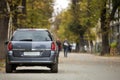 Gray shiny car parked in quiet area on asphalt road on blurred bokeh background on bright sunny day. Transportation and parking