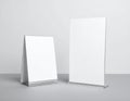 Two blank white table talker stands of different sizes on a gray surface image photo Royalty Free Stock Photo