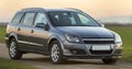 Gray silver new shiny car moving on empty rural road on blurred green meadows and clear foggy sky copy space background. Royalty Free Stock Photo