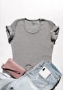 Gray slim fit t-shirt with jeans and leather pink feminine bag above white background. Mock up flat lay in minimalist style Royalty Free Stock Photo