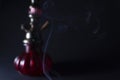 Gray smoke on a background of a red hookah on a black background. Royalty Free Stock Photo
