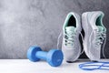 Gray sneakers , 1 blue dumbbell, skipping rope, on a gray