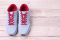 Gray sneakers running with red laces on a wooden background