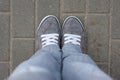 Gray sneakers with white laces stand on the tile, top view, comfortable shoes for walking around the city. gray bottom clothes