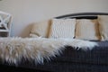 Gray sofa with boucle upholstery fabric and white decorative fluted cushions. White rug or bedspread made of faux fur