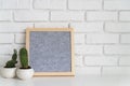 Gray square mock up felt letter board with small succulents on white brick background