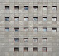 Gray stone modern facade of an office building with windows reflecting the sky