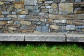 Gray stone wall with solid wood bench folded without cement and concrete. stone quartzite durable retaining wall, garden park. tri