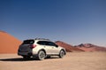 Gray Subaru in the sand of the Namib desert at a bright sky