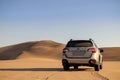 Gray Subaru in the sand of the Namib desert at a bright sky.