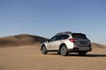 Gray Subaru in the sand of the Namib desert at a bright sky.