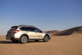 Gray Subaru in the sand of the Namib desert at a bright sky.