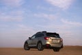 Gray Subaru in the sand of the Namib desert at a bright sunset