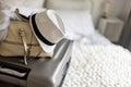 Gray suitcase with handbag and summer hat packing ready to travel vacation on bed at home or hotel