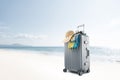 gray suitcase with pareo and hat on tropical beach