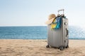 gray suitcase with pareo and hat on tropical beach