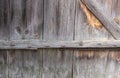 Gray, sun-faded boards with knots, streaks, fastened with planks in different directions, with bent rusty nails