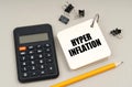 On a gray surface, a calculator, a pencil and a notepad with the inscription - Hyper inflation