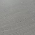 Gray surface featuring numerous fine scratches and small black specks. The overall Royalty Free Stock Photo