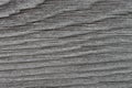 The gray surface of an old weathered wooden board. Horizontal wavy pattern of annual rings. Dark background or wallpaper. The Royalty Free Stock Photo